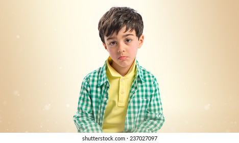 Sad Brunette Kid Over Ocher Background 