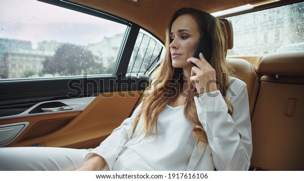 Sad business lady talking
on smartphone in business car. Closeup tired businesswoman speaking
on phone in automobile. Beautiful ceo woman sitting in salon of
modern car.