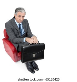 Sad businessman sitting in a small armchair.