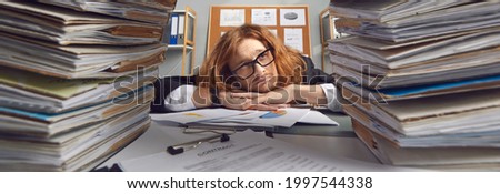 Sad busy clerk looking at too much paperwork. Panorama background banner with tired worker at messy office desk full of disorganized papers, many work contracts and lots of corporate bookkeeping data
