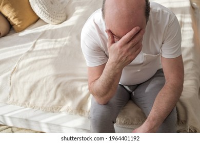 Sad Caucasian Man Sitting On His Bed With His Head On His Hand