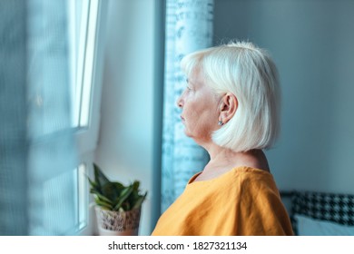 Sad Caucasian Woman 50 Years Old Looks Out The Window. Hope Concept. Concept Home Quarantine, Prevention COVID-19, Coronavirus