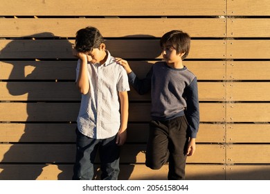 Sad Child Care. Two Young Boys. Giving Help Concept. Kid Giving Support To Each Other. Golden Hour Scene Of Upset Child With Hand On Face. Hand On Shoulder.