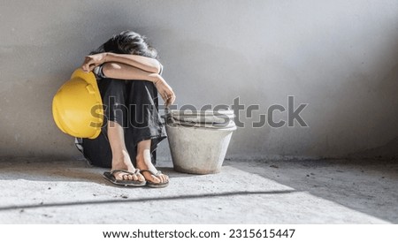 Sad child labor girl relaxing from construction work. World Day Against Child Labour concept.