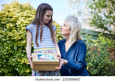 Sad Child With Mother Burying Pet Guinea Pig In Garden At Home