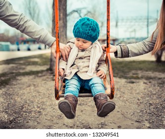 Sad child on a swing, in-between her  divorced parents holding her separately.