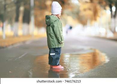 sad child puddles rain / autumn photo of a child for a walk, park rain wet clothes