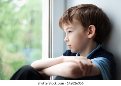 Sad Child Sitting On Window