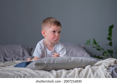 Sad child. Sulky little boy lying on the bed on arms. concept of three years crisis.