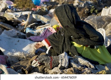 A sad child is working at a garbage dump