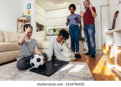 Sad Children Standing In Front Of A TV With Broken Screen Holding A Ball. Home Insurance Concept.