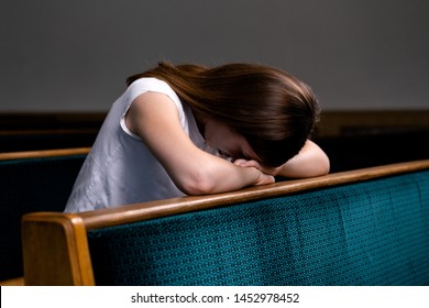 A Sad Christian Girl In White Shirt Is Sitting And Praying With Humble Heart In The Church.