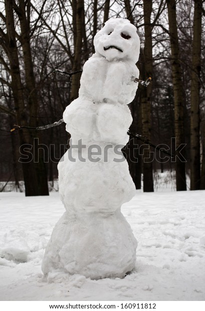 Sad\
Christmas snowman sitting in a snowy outdoors\
