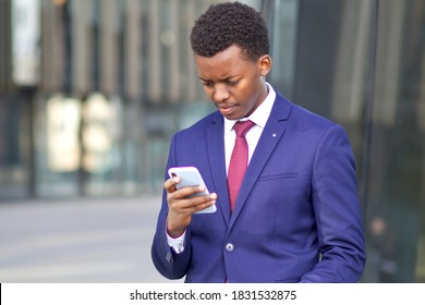 Sad Concentrated Upset Frustrated Black African Afro American Man Looking At Screen Of His Smartphone. Unhappy Office Worker, Businessman In Formal Suit Outdoors. Problems With Cell Mobile Phone. 