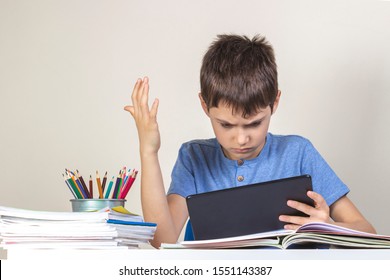 Sad Confused Child With Tablet Computer Sitting At Table With Books Notebooks