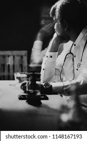 Sad Depressed 40s Asian Or Muslim Doctor Sitting By The Window, Tea Gone Cold, He Looking Outside Or Flew Away.  Doctors Get Sad, Like Anyone Else.Doctors And Depression Concept.Black And White Image.