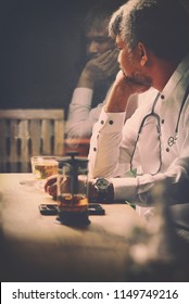 Sad Depressed 40s Asian Muslim Doctor Sitting By The Window,Man With Beard And Mustache With Stethoscope And Tea Cup Looking Outside Or Flew Away.Doctors And Depression Concept.Vintage Color Tone.