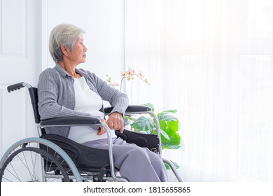 Sad and depressed asian senior woman in a wheelchair at home. Copy space on the window. - Powered by Shutterstock