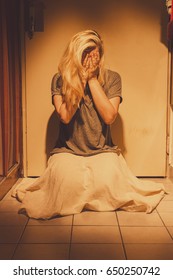 Sad, Depressed And Lonely Woman Kneeling On A Floor Tiles, Crying, In A Skirt, With A Long Blond Hair