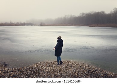 Sad and depressed looking Girl standing near a frozen lake 