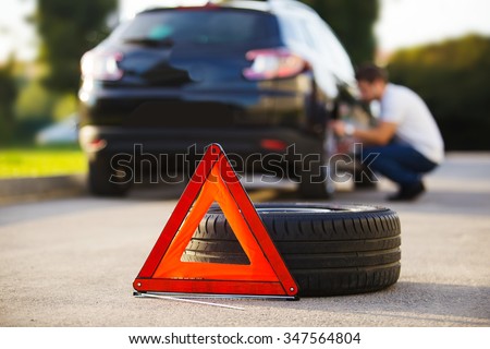 Sad and depressed man sitting near car with punctured tire