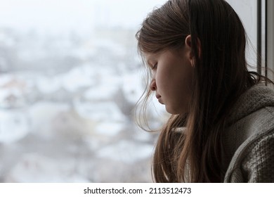 Sad Depressed Teen Girl sitting Alone and Depressed on the windowsill. Unhappy teenager is upset with negative thoughts. Help children.