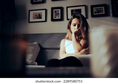 
Sad Depressed Woman Alone at Home Sitting on a Sofa. Unhappy lady feeling lonely and anxious in pain
