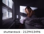 Sad depressed woman in bed. Lonely person with stress, insomnia and trouble sleeping. Anxiety, sorrow, solitude, grief or panic. Restless tired and desperate girl crying with emotion.