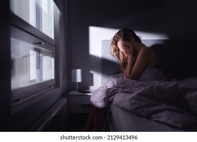 Sad depressed woman in bed. Lonely person with stress, insomnia and trouble sleeping. Anxiety, sorrow, solitude, grief or panic. Restless tired and desperate girl crying with emotion.