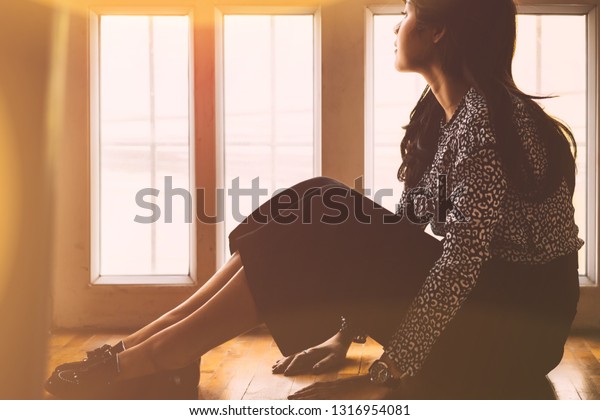 Sad and depressed woman sitting on
the floor in the living room with backlit and lens flare,sad
mood,feel tired, lonely and unhappy concept. vintage
tone