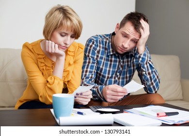 Sad, depressed young couple paying bills.