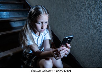 Sad depressed young girl victim of cyberbullying by mobile smart phone sitting on stairs feeling lonely, unhappy, hopeless and abused. Bullied by text message. Dark light - Powered by Shutterstock