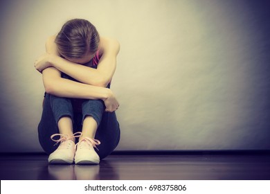 Sad Depressed Young Teenage Girl Sitting By Wall Hiding Face. School, Adolescence, Home Violence, Unwanted Love Problems.