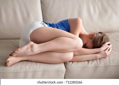 Sad Depressed Young Woman Lying On Sofa, Covers Face With Hands, Feeling Exhausted After Emotional Breakdown, Frustrated Teenager Having Problems, Tired Upset Teen Sleeping On Couch In Fetal Position