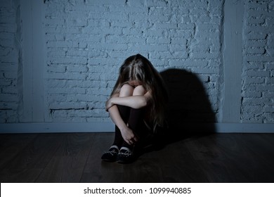 Sad Desperate Young Girl Suffering From Bulling And Harassment Felling Lonely, Unhappy Desperate And Hopeless Sitting Against The Wall, Dark Light. School Isolation, Abuse And Bullying Concept