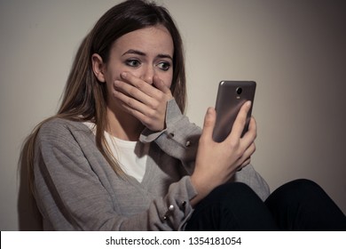 Sad Desperate Young Teenager Female Girl On Smart Phone Suffering From Online Bulling And Harassment Felling Lonely And Hopeless Sitting On Bed At Night. CYberbullying And Dangers Of Internet Concept.