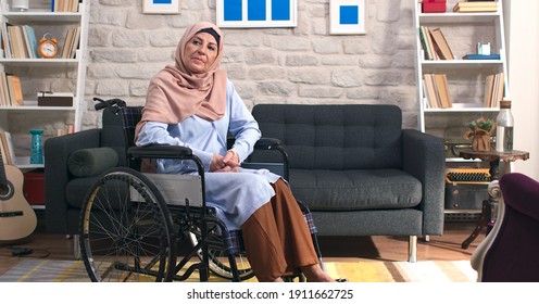 Sad Disabled Old Woman With Turban In A Wheelchair Alone In The Living Room At Home.