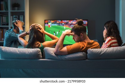 Sad disappointed group of friends watching a football match on TV, their team is losing the match - Powered by Shutterstock