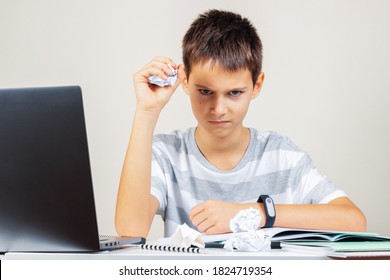 Sad Dissapointed Kid Doing Homework On Laptop Computer. Boy Hand Squeezing A Crumpled Ball Of Paper. School, Remote Education, Online Learning At Home