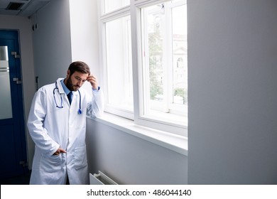 Sad doctor standing in hospital corridor