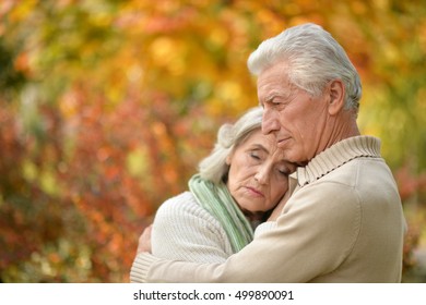 Sad Elderly Couple Standing Embracing Outdoors