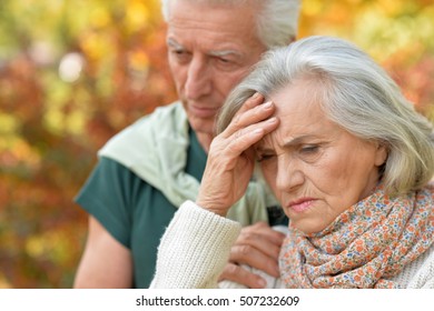 Sad Elderly Couple Standing Embracing Outdoors