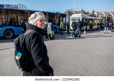 A sad elderly woman with a Ukrainian flag in a backpack near the evacuation buses. Humanitarian catastrophe in Ukraine. War between Ukraine and Russia. People are leaving the hot spots in Ukraine