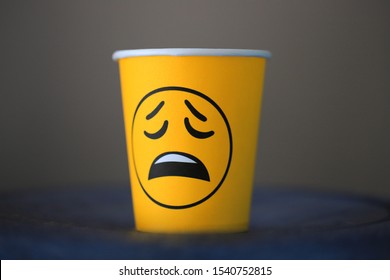 Sad Emotion Emoji On A Paper Cup With Coffee In The Office. Boring Office Work.