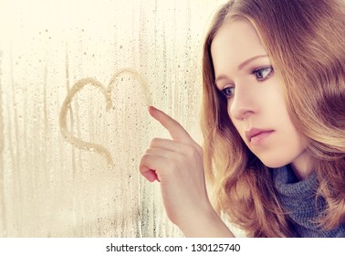 Sad Enamored Girl Draws A Heart On The Window In The Rain