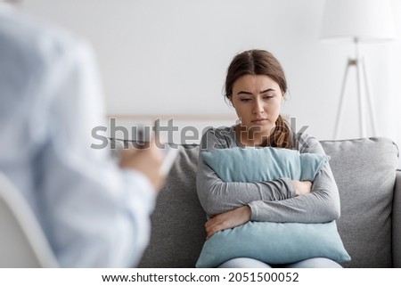Sad european young woman suffering from depression and consults with psychologist in clinic, empty space. Mental therapy, survive personal crisis, individual counselling, problems and treatment