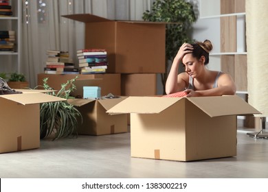 Sad evicted tenant moving home boxing belongings sitting on the floor in the night - Shutterstock ID 1383002219