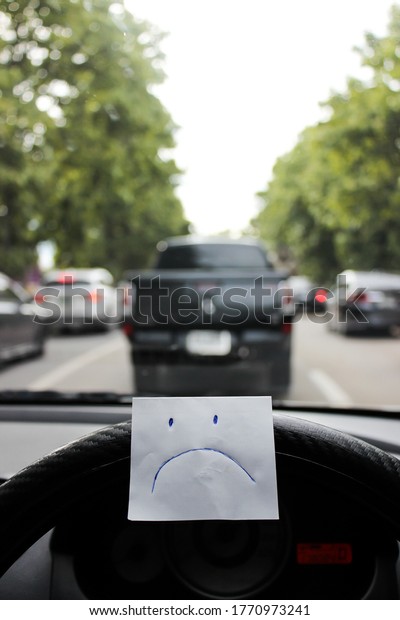 sad face emotion paper note in traffic jam due to\
road accident point of view first person in car during holiday\
travel in Thailand Asia.