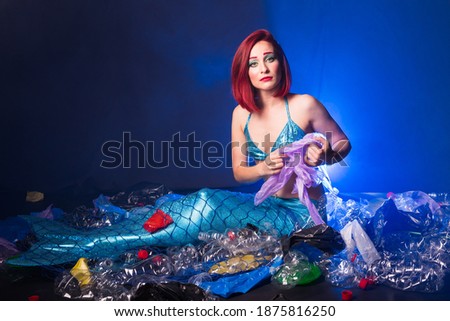 Sad fairytale mermaid in polluted ocean. Plastic trash and garbage in water. Environmental problem, plastic bag and bottles polluting a coral reef.