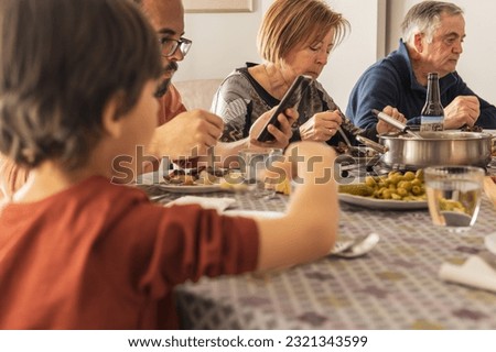 Sad family having meal together but ignoring each other. checking mobile phone during lunch